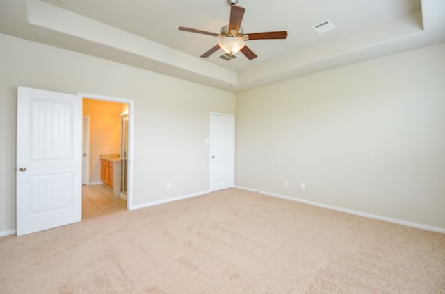 unfurnished bedroom with baseboards, light carpet, ensuite bath, and visible vents