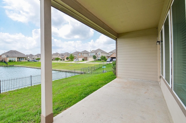 view of patio / terrace with a water view, fence, and a residential view