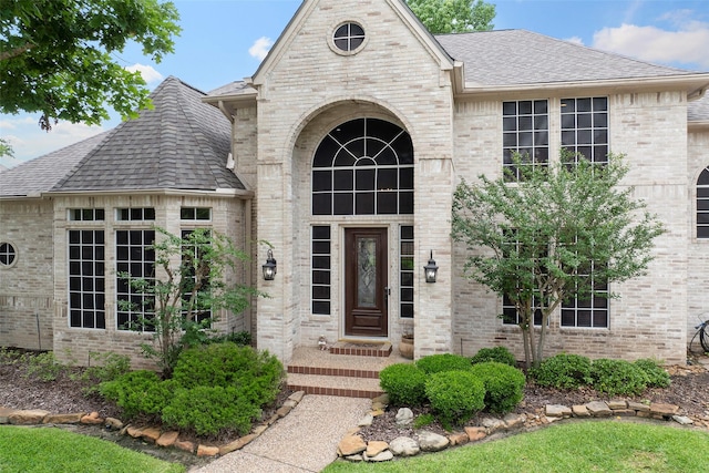 property entrance with brick siding and roof with shingles