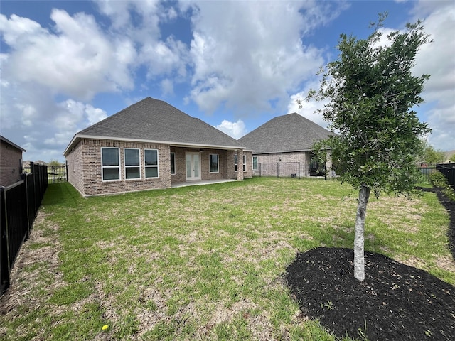 back of house with a fenced backyard, a lawn, a patio area, and brick siding