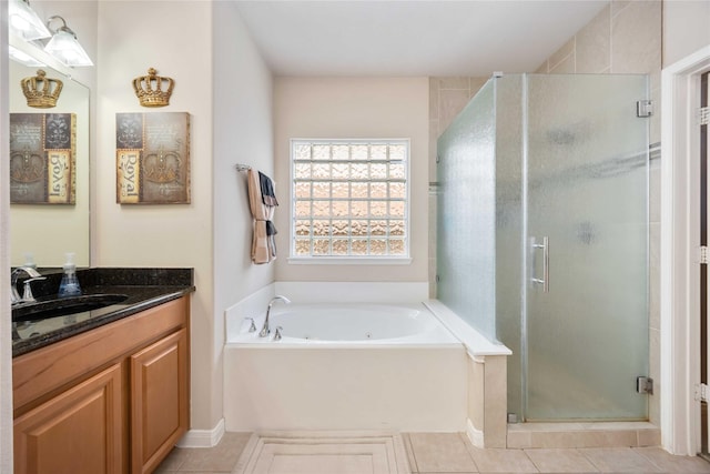 bathroom featuring tile patterned flooring, vanity, a stall shower, and a jetted tub