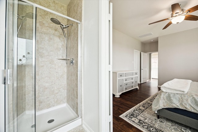bathroom featuring ceiling fan, visible vents, a shower stall, and wood finished floors