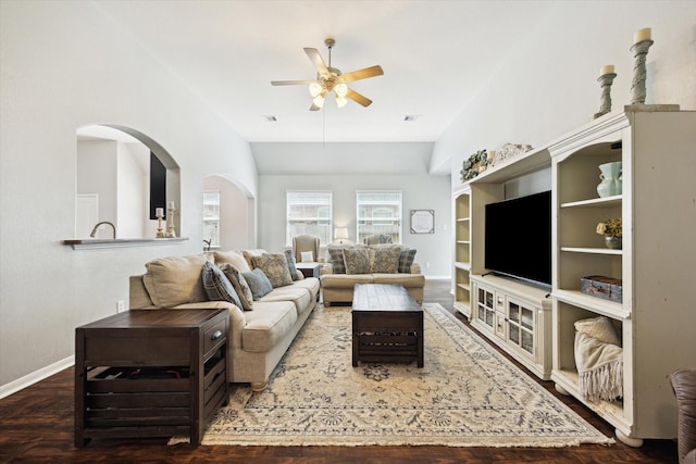 living room featuring visible vents, wood finished floors, baseboards, ceiling fan, and arched walkways