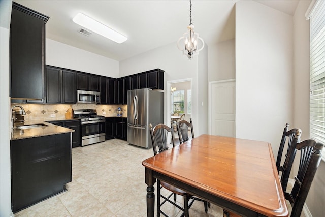 kitchen featuring decorative backsplash, visible vents, appliances with stainless steel finishes, a sink, and dark cabinets