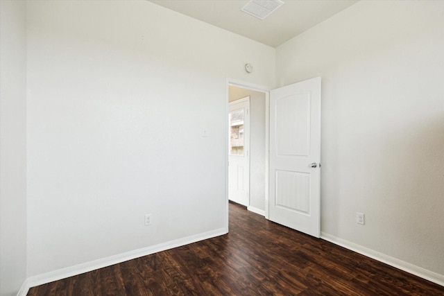 unfurnished room with visible vents, dark wood-style flooring, and baseboards