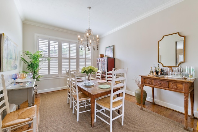 dining area featuring crown molding, baseboards, a chandelier, and wood finished floors