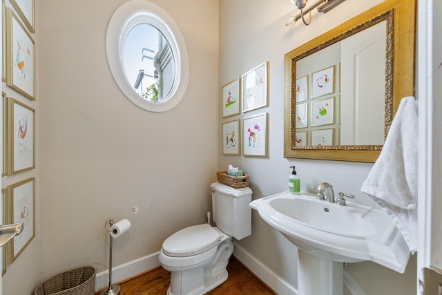 half bath featuring baseboards, wood finished floors, and toilet
