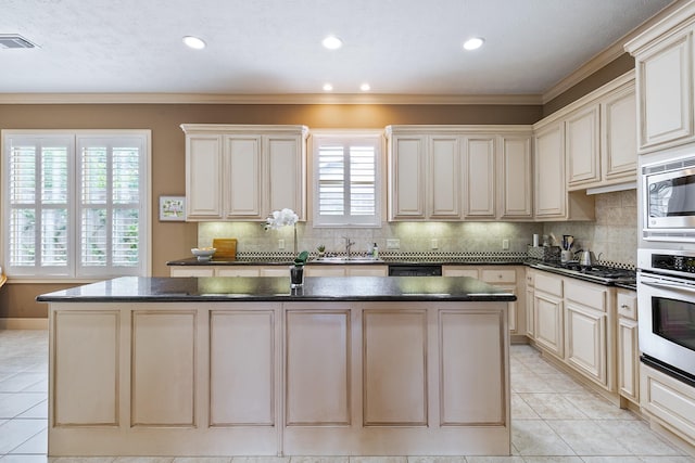 kitchen with oven, light tile patterned flooring, stainless steel microwave, a kitchen island, and visible vents