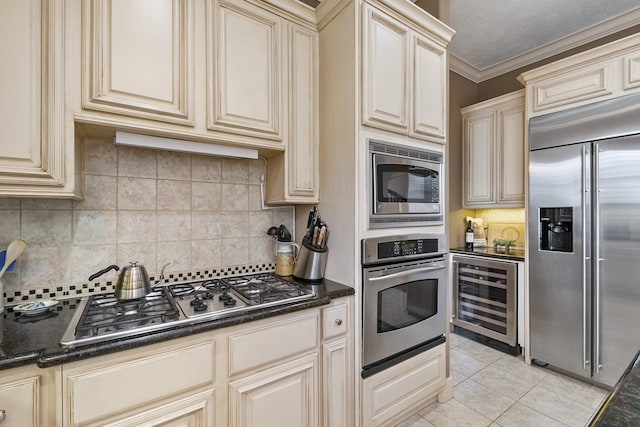 kitchen with tasteful backsplash, built in appliances, cream cabinets, and beverage cooler