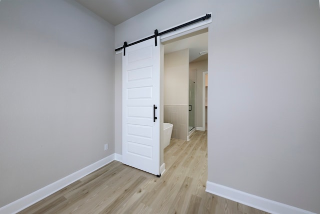 interior space featuring light wood-style floors, a barn door, and baseboards