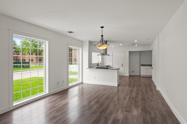 unfurnished living room featuring a healthy amount of sunlight, baseboards, dark wood-style floors, and visible vents