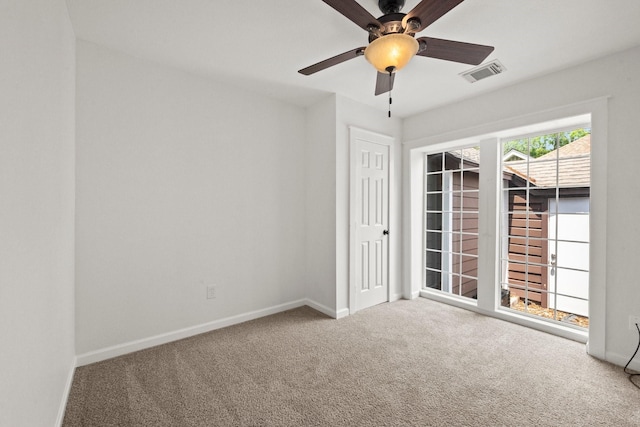 carpeted spare room with baseboards, visible vents, and ceiling fan