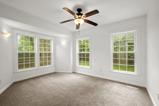 carpeted empty room with a ceiling fan and baseboards