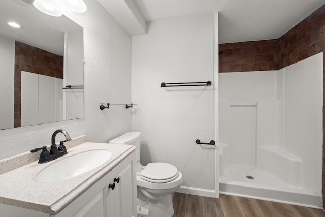 bathroom featuring vanity, wood finished floors, toilet, baseboards, and a shower stall