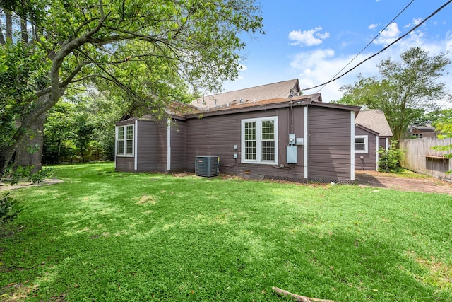 back of house with a lawn, a shingled roof, central air condition unit, and fence