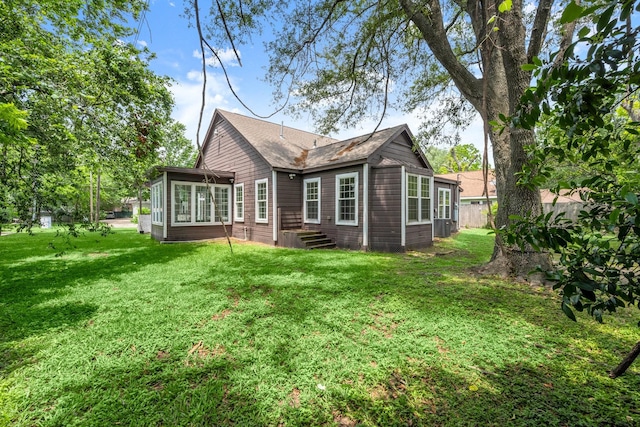 back of house featuring a lawn, central AC, fence, and a sunroom