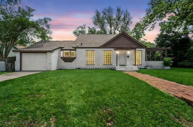 ranch-style home featuring brick siding, a garage, a front lawn, and driveway