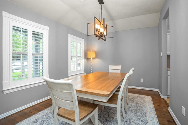 dining space with an inviting chandelier, baseboards, lofted ceiling, and dark wood-type flooring