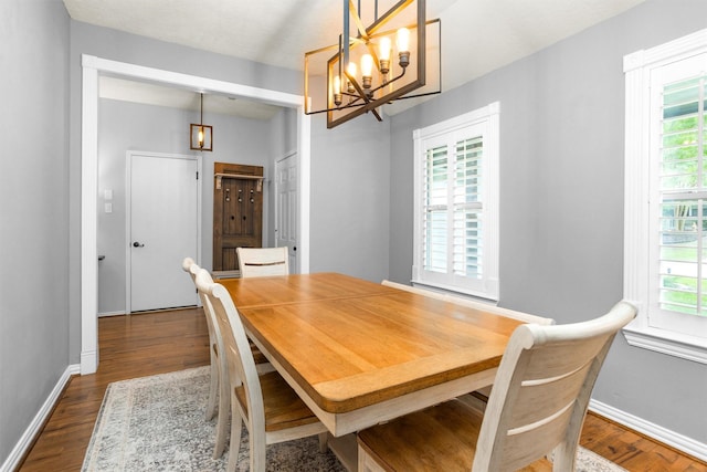 dining space featuring an inviting chandelier, dark wood finished floors, and a wealth of natural light