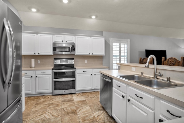 kitchen with a sink, appliances with stainless steel finishes, white cabinetry, and light countertops