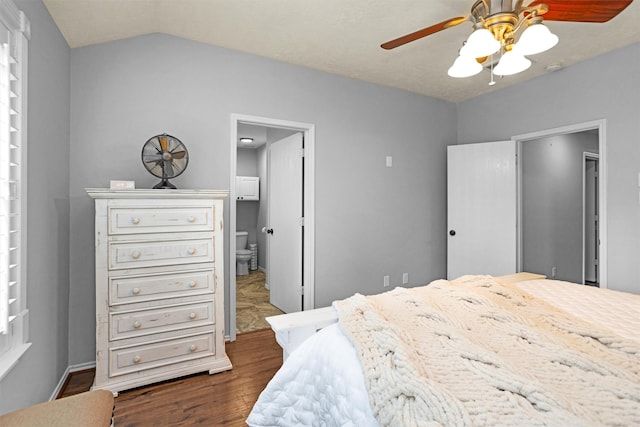bedroom featuring dark wood-type flooring, a ceiling fan, connected bathroom, and lofted ceiling