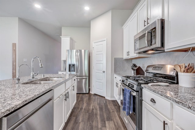 kitchen featuring light stone countertops, dark wood-type flooring, white cabinets, a sink, and stainless steel appliances