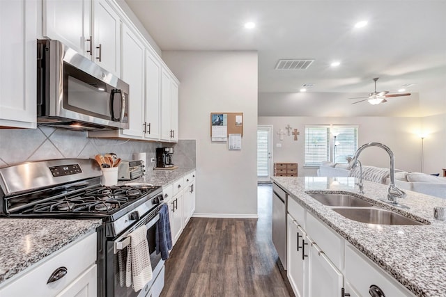 kitchen with dark wood-style floors, white cabinetry, a sink, appliances with stainless steel finishes, and backsplash