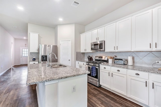 kitchen featuring visible vents, dark wood-type flooring, a sink, backsplash, and stainless steel appliances
