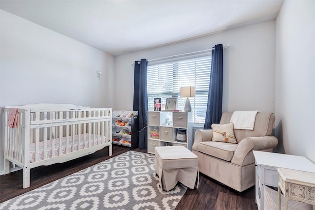 bedroom with a crib and wood finished floors
