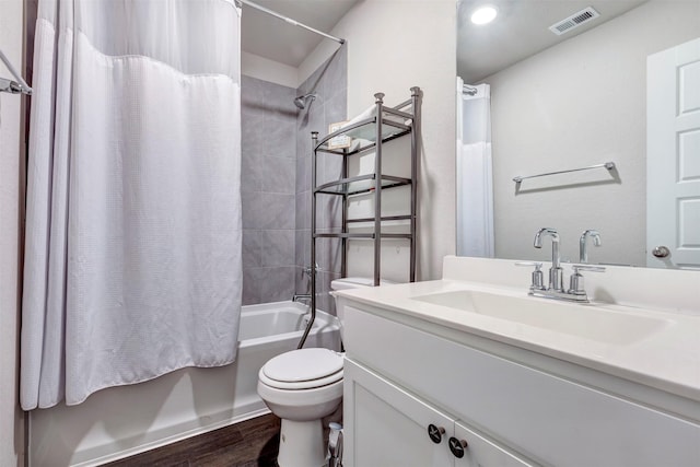 bathroom with visible vents, wood finished floors, shower / tub combo, vanity, and toilet