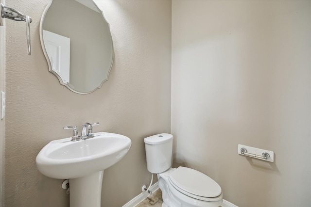 bathroom with baseboards, a sink, and toilet