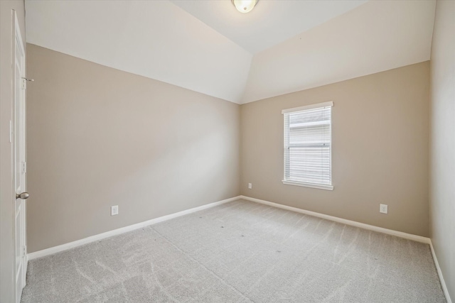 empty room featuring baseboards, light colored carpet, and lofted ceiling