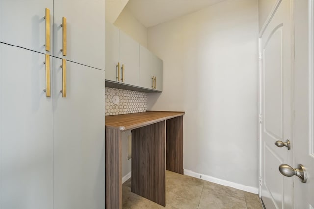 bar with backsplash, light tile patterned flooring, and baseboards