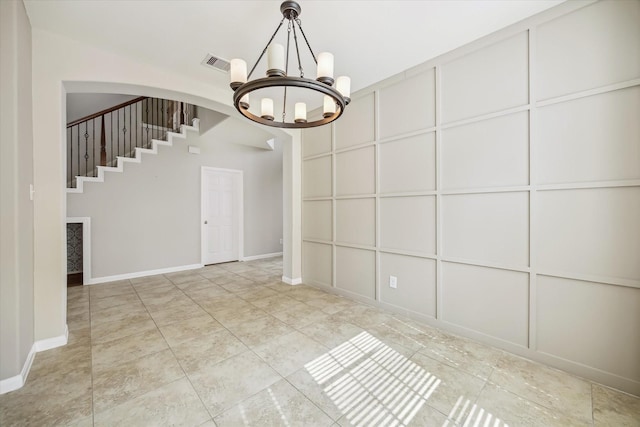 unfurnished dining area featuring visible vents, stairs, baseboards, arched walkways, and a notable chandelier