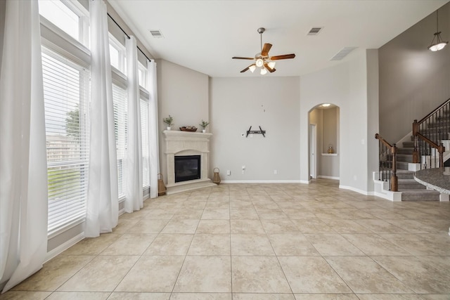 unfurnished living room featuring visible vents, arched walkways, plenty of natural light, and a ceiling fan