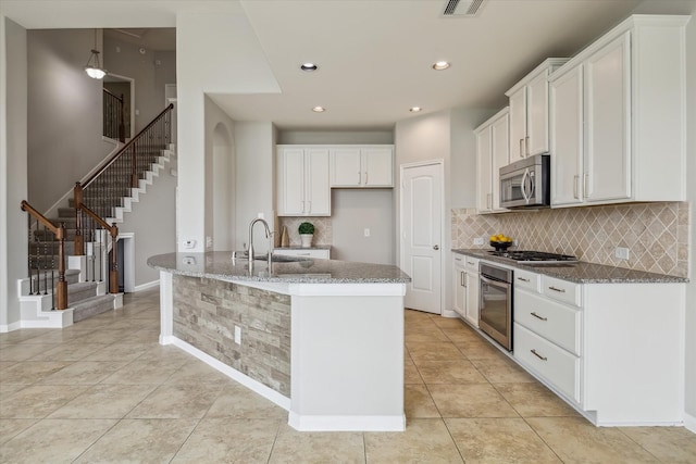 kitchen with a sink, decorative backsplash, stone counters, and stainless steel appliances