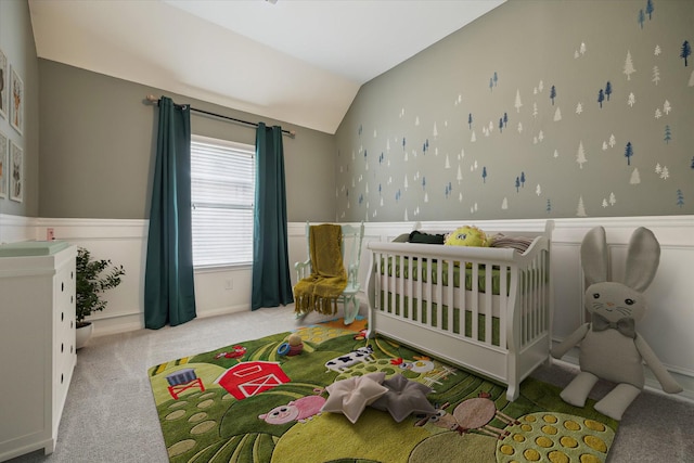 carpeted bedroom featuring lofted ceiling and a wainscoted wall