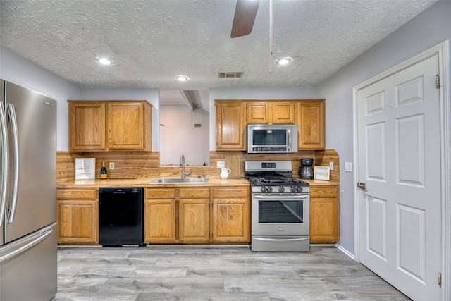 kitchen featuring visible vents, a sink, a textured ceiling, and stainless steel appliances