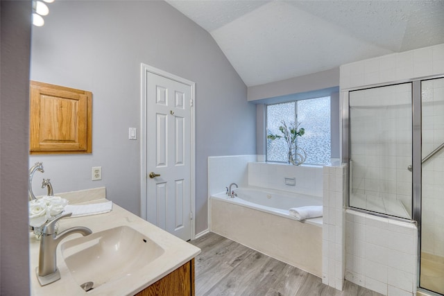 bathroom with wood finished floors, lofted ceiling, a bath, a sink, and a stall shower