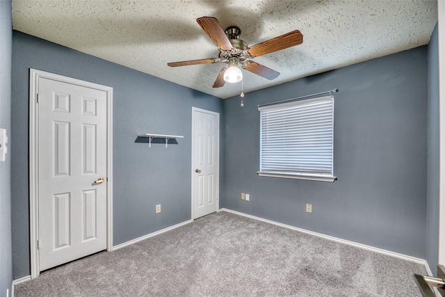 unfurnished bedroom featuring baseboards, carpet flooring, a textured ceiling, and ceiling fan