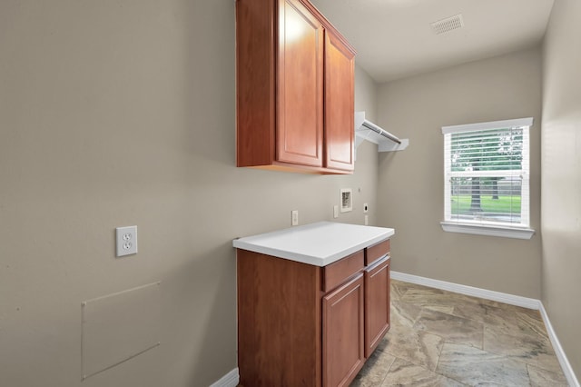 washroom with baseboards, washer hookup, cabinet space, and visible vents