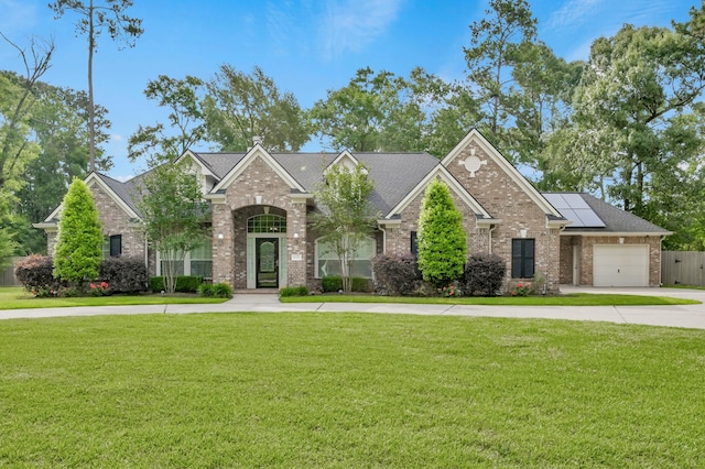 craftsman-style home with brick siding, an attached garage, a front yard, and solar panels