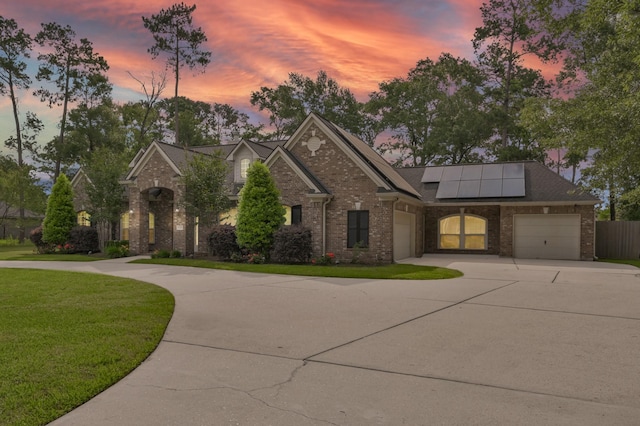 view of front of home featuring curved driveway, a front lawn, roof mounted solar panels, and brick siding