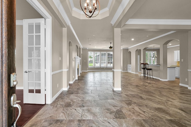 foyer entrance with baseboards, ornamental molding, arched walkways, and ceiling fan with notable chandelier