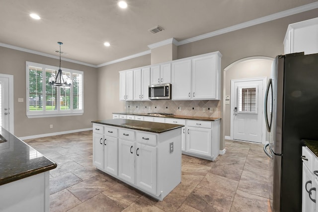 kitchen with decorative backsplash, visible vents, crown molding, baseboards, and stainless steel appliances