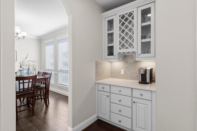 bar featuring baseboards, arched walkways, dark wood-style flooring, and backsplash