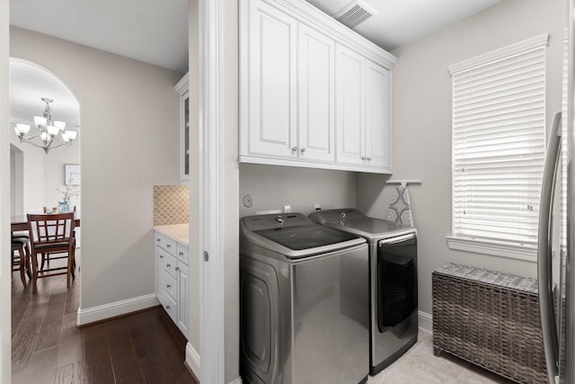 laundry room featuring visible vents, arched walkways, cabinet space, a chandelier, and washer and dryer