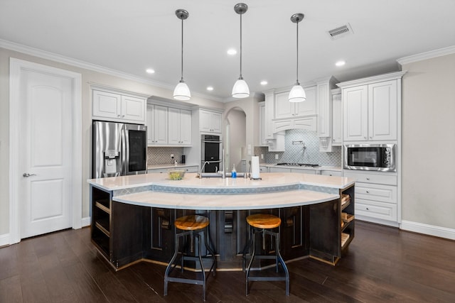 kitchen with a large island, light countertops, white cabinets, appliances with stainless steel finishes, and backsplash