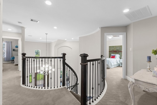 hallway with visible vents, an upstairs landing, and light carpet