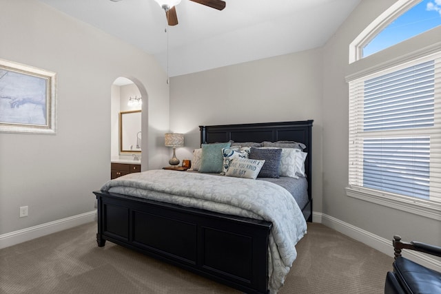 bedroom with arched walkways, baseboards, and light carpet